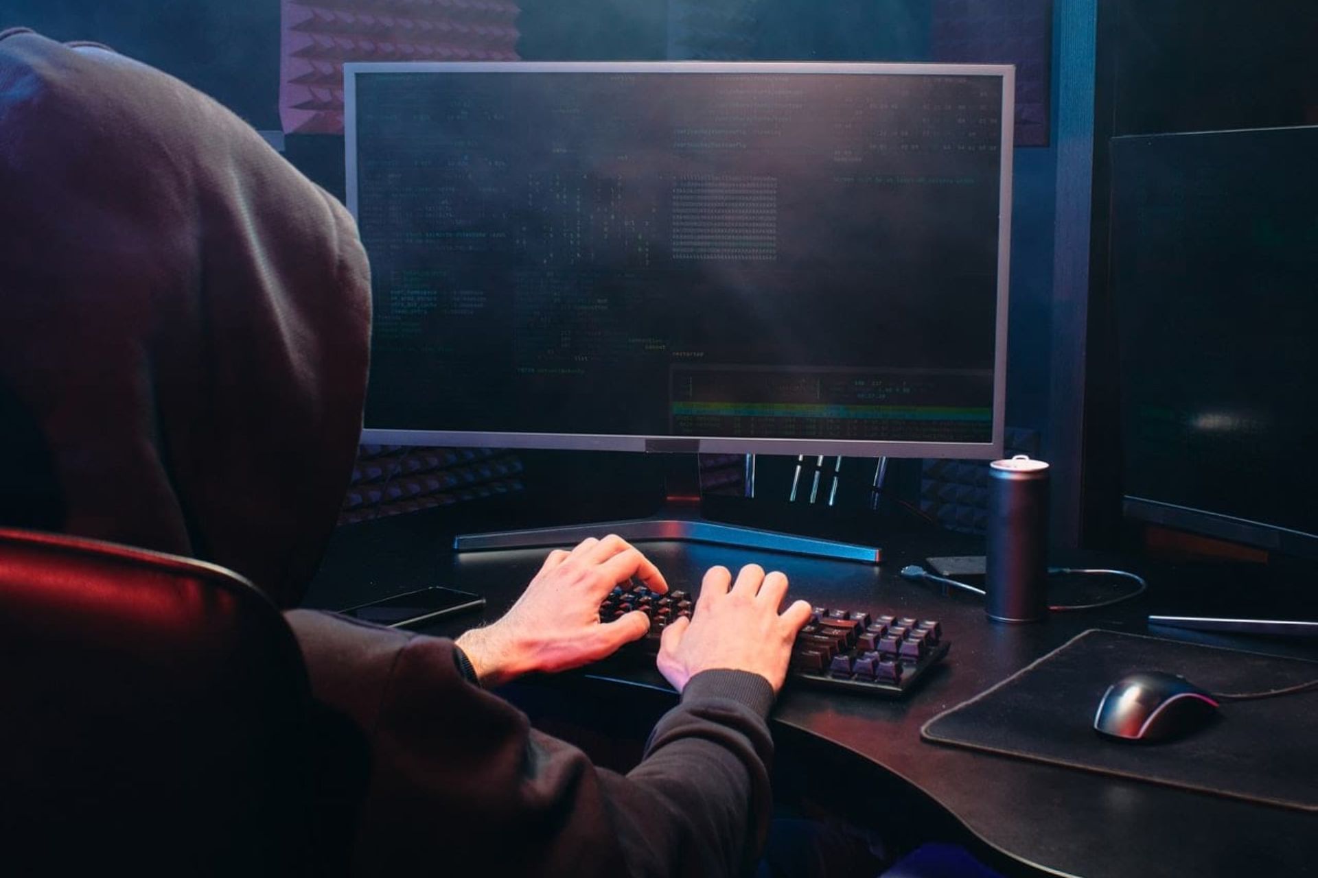 man with a hoodie typing on keyboard