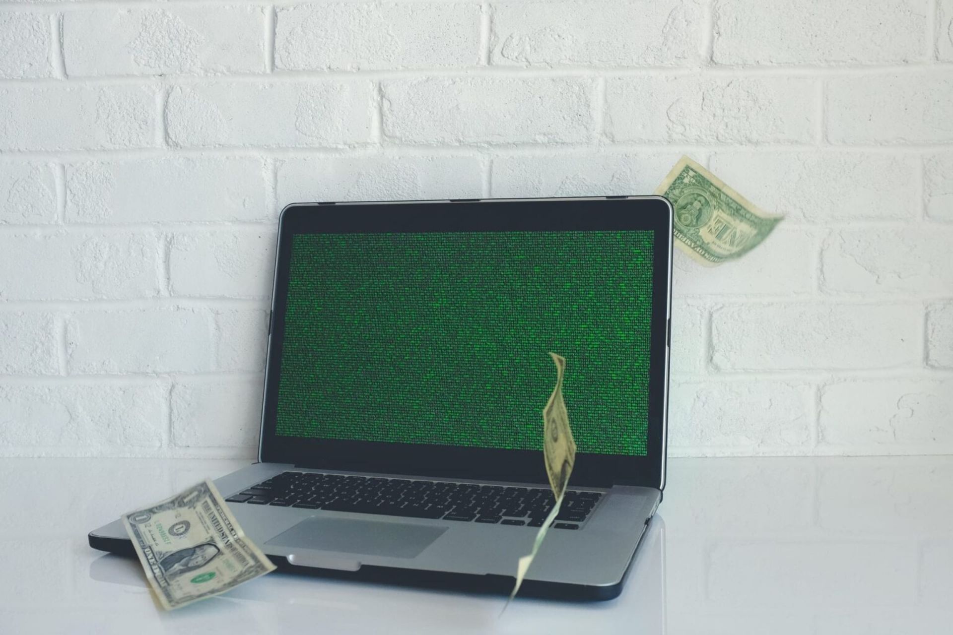 laptop with green screen and dollar bills falling