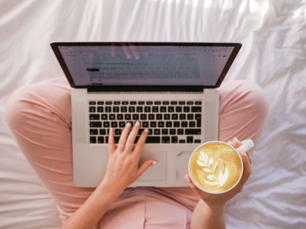 a woman holding a cup of coffee and a laptop