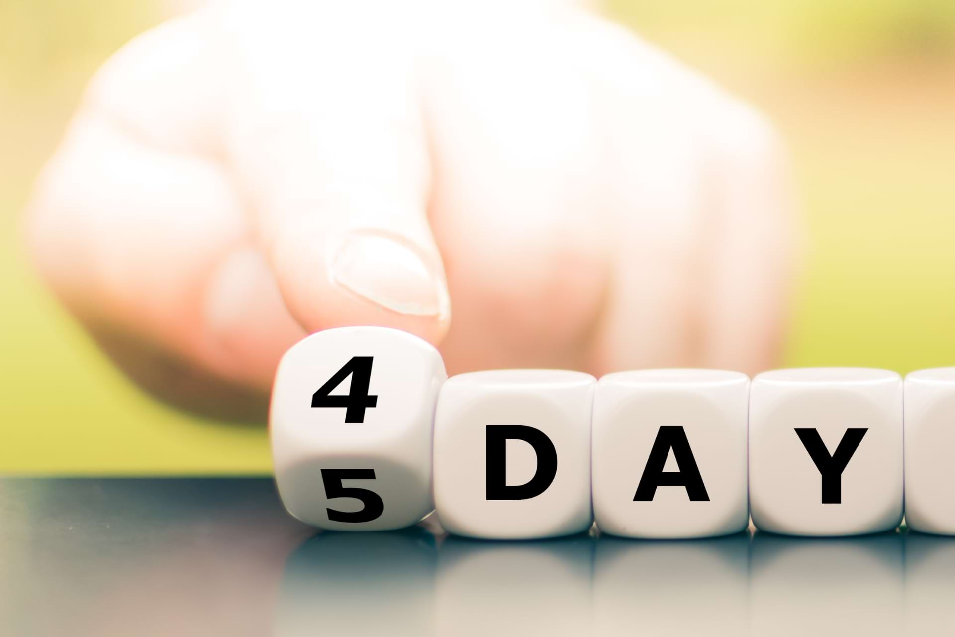 a hand arranging blocks that say 4 DAY